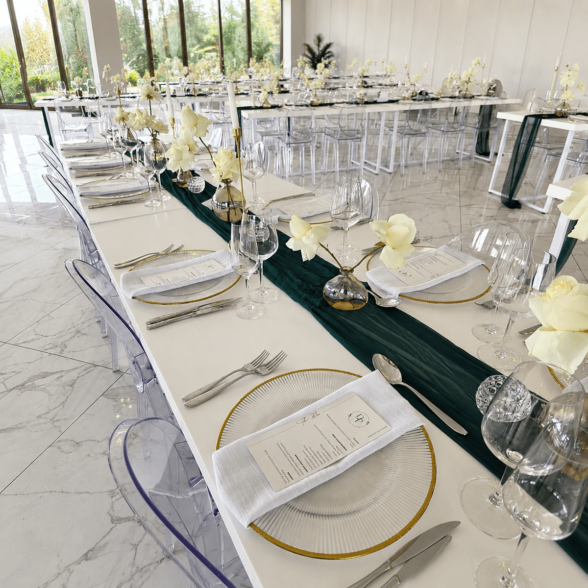 Long banquet table styled with menus and a green runner