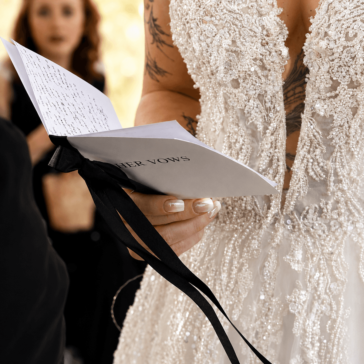 Bride holding a 'Her vows' vow booklet with ribbon